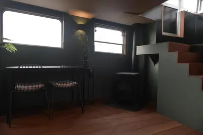 a room with a table and two chairs and two windows at EUPHRATE HOUSeBOAT in Amsterdam