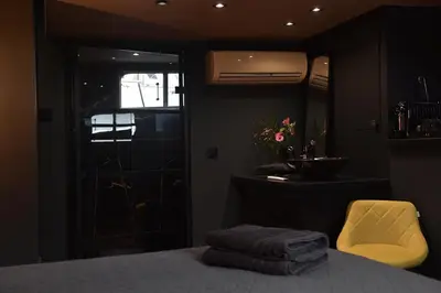 a bedroom with a bed with a yellow chair and a mirror at EUPHRATE HOUSeBOAT in Amsterdam