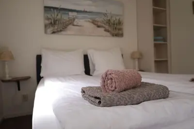 a bed with a pink towel on top of it at De Blokhut in Egmond aan den Hoef