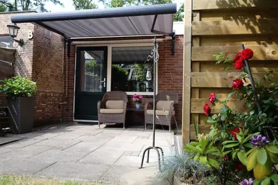 a black awning over a patio with two chairs at De Blokhut in Egmond aan den Hoef