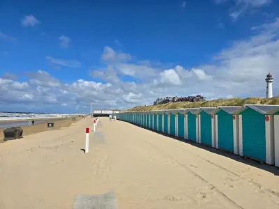 a view of a beach with a blue and white building at De Blokhut in Egmond aan den Hoef