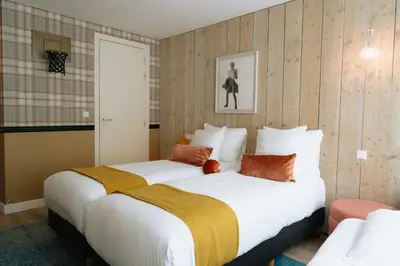 two beds in a hotel room with wood paneling at Max Brown Hotel Canal District, part of Sircle Collection in Amsterdam