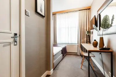 a hotel room with a bed and a desk and a window at The Delphi - Amsterdam Townhouse in Amsterdam