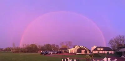 a rainbow in the sky over a field with houses at The Waverly House in Ouderkerk aan de Amstel
