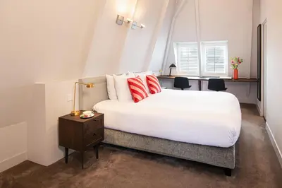 a bedroom with a large white bed with red pillows at Maison ELLE Amsterdam in Amsterdam