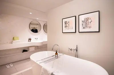 a white bathroom with a tub and a sink at Maison ELLE Amsterdam in Amsterdam