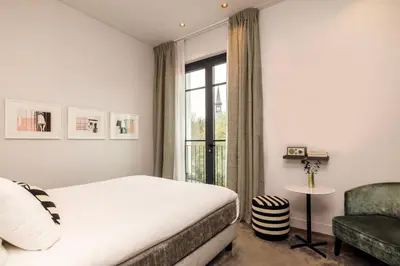 a bedroom with a bed and a chair and a window at Maison ELLE Amsterdam in Amsterdam