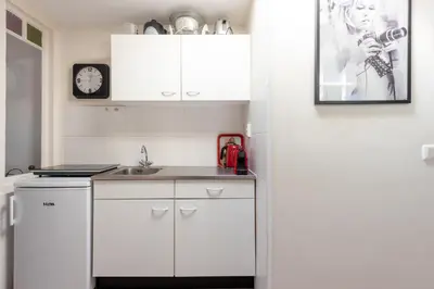 a kitchen with white cabinets and a sink and a clock at Gezellig appartement in de mooie oude binnenstad van Alkmaar in Alkmaar