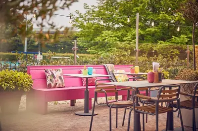 a pink bench and tables and chairs on a patio at WestCord Art Hotel Amsterdam 4 stars in Amsterdam