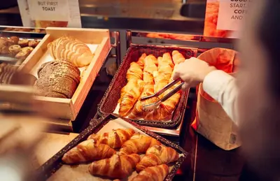 a person reaching for a tray of pastries in a bakery at WestCord Art Hotel Amsterdam 4 stars in Amsterdam