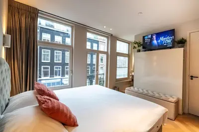 a bedroom with a bed and a flat screen tv at Renovated Parkside Gem - 2 person studio in the Pijp in Amsterdam