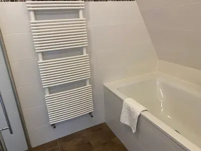 a bathroom with a white towel rack next to a tub at Katwijk Center, 1 min away from the beach! in Katwijk aan Zee