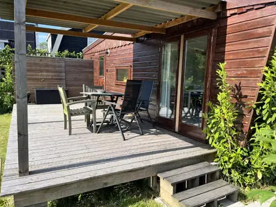 a wooden deck with a table and chairs on it at Vrijstaand chalet met veel buitenruimte en veranda in Zuid-Scharwoude