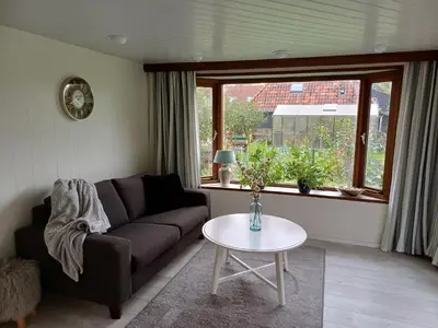 a living room with a couch and a table at Vrijstaand chalet met veel buitenruimte en veranda in Zuid-Scharwoude