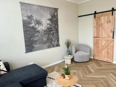 a living room with a blue couch and a table at Amsterdam Beach Apartment 33, Private Garden in Zandvoort