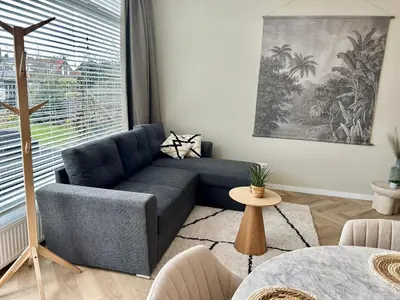 a living room with a blue couch in front of a window at Amsterdam Beach Apartment 33, Private Garden in Zandvoort