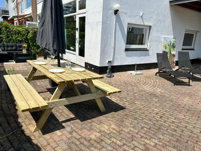 a wooden picnic table sitting on a brick patio at Amsterdam Beach Apartment 17, incl Parking + Garden in Zandvoort