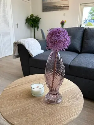 a vase with purple flowers sitting on a table at Amsterdam Beach Apartment 17, incl Parking + Garden in Zandvoort