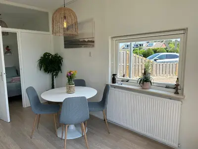 a dining room with a table and chairs and a window at Amsterdam Beach Apartment 17, incl Parking + Garden in Zandvoort