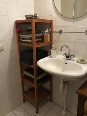 a bathroom with a sink and a shelf with towels at Great House for Two in Amsterdam in Amsterdam