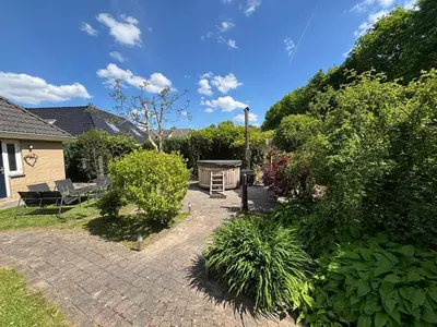 a garden with a brick patio with a grill at The Poplar Place, Comfort & Hottub in Zeewolde