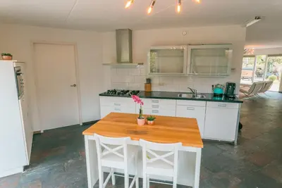 a kitchen with a wooden table and white cabinets at The Poplar Place, Comfort & Hottub in Zeewolde