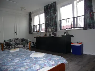 a bedroom with a bed and two windows at B&B “Te Warskip bij BlokVis” in Medemblik