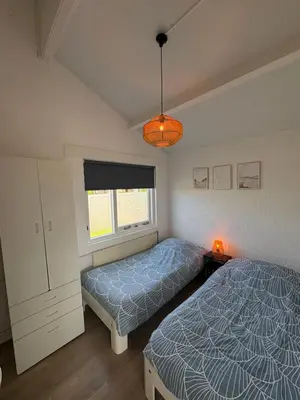 a bedroom with two beds and a window at Buenaventura in Egmond aan den Hoef