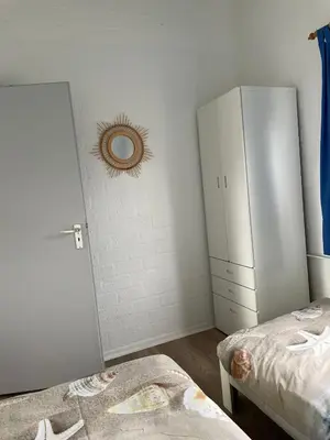 a bedroom with two beds and a white cabinet at Buenaventura in Egmond aan den Hoef