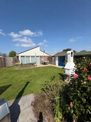 a yard with a house and a garden with flowers at Buenaventura in Egmond aan den Hoef