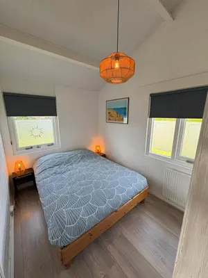 a bedroom with a bed and two windows at Buenaventura in Egmond aan den Hoef