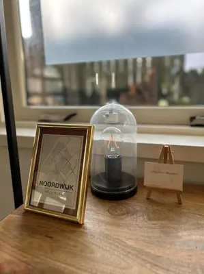 a candle in a glass dome and a picture on a table at Have a nice stay! - Vakantiehuis BijSaar in Noordwijk