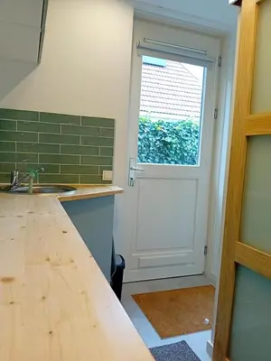 a kitchen with a white door and a window at Oudaen 36 in Lelystad
