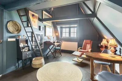 a attic room with a ladder and a table and chairs at Boutique Hotel Jongwijs Westzaan in Westzaan