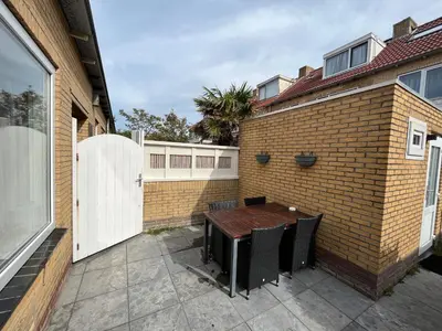 a brick wall with a table and a white fence at Modern strandhuis 350 m van zee Egmond aan Zee in Egmond aan Zee