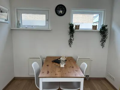a dining room table with chairs and a clock on the wall at Modern strandhuis 350 m van zee Egmond aan Zee in Egmond aan Zee