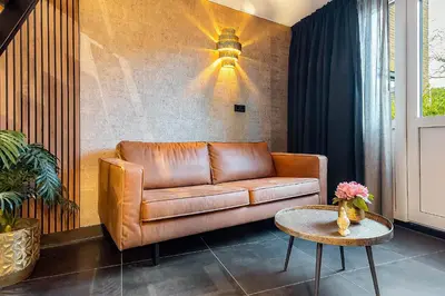 a brown leather couch in a living room with a table at Loft 29 in Zandvoort