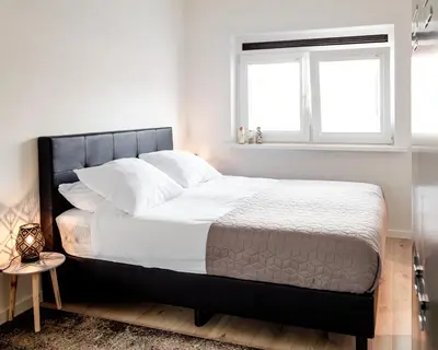 a bedroom with a bed with white sheets and a window at M&M Studio's 1 & 2 in Zandvoort