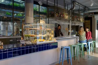 a group of people standing at a counter in a restaurant at Stayokay Hostel Amsterdam Vondelpark in Amsterdam