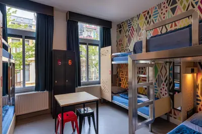 a room with bunk beds and a table and stool at Stayokay Hostel Amsterdam Vondelpark in Amsterdam