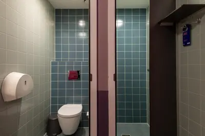 a bathroom with a toilet and green tiles at Stayokay Hostel Amsterdam Vondelpark in Amsterdam