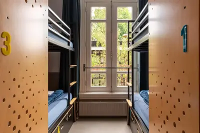 a room with two bunk beds and a window at Stayokay Hostel Amsterdam Vondelpark in Amsterdam