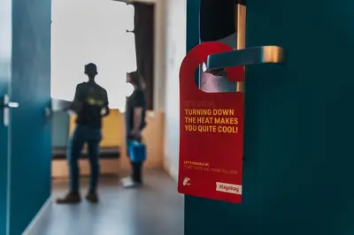 a red sign on a door with people standing in a hallway at Stayokay Hostel Amsterdam Vondelpark in Amsterdam
