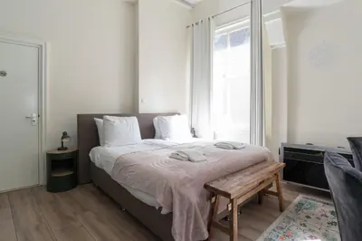 a bedroom with a bed with a bench and a window at 1001 Nights Boutique Lofts in Haarlem