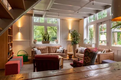 a living room with a lot of furniture and windows at Stayokay Hostel Soest in Soest