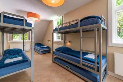 a room with three bunk beds and two windows at Stayokay Hostel Soest in Soest