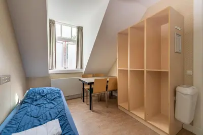 a small room with a bed and a desk and a table at Stayokay Hostel Soest in Soest