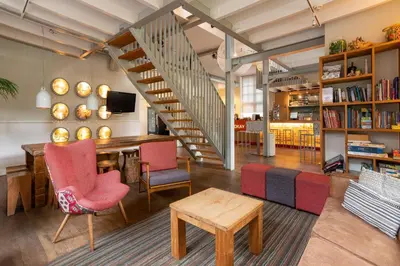 a living room with a staircase and a table and chairs at Stayokay Hostel Soest in Soest