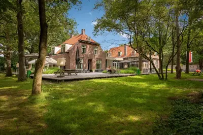 a large house with a green yard with trees at Stayokay Hostel Soest in Soest