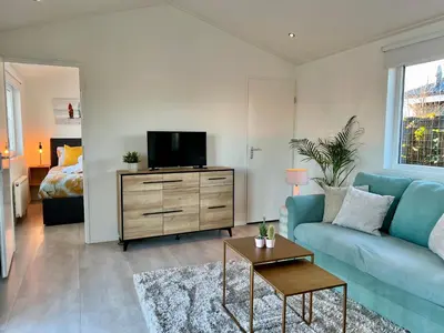 a living room with a blue couch and a tv at NEW - The Surf Shack - on a lake near Amsterdam! in Vinkeveen